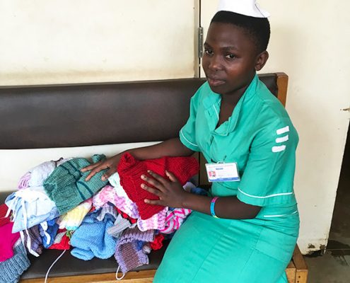 A nurse helping distribute baby clothes