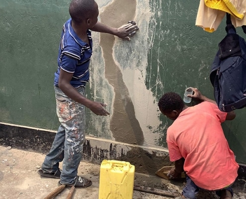 Street boys learning how to repair a wall