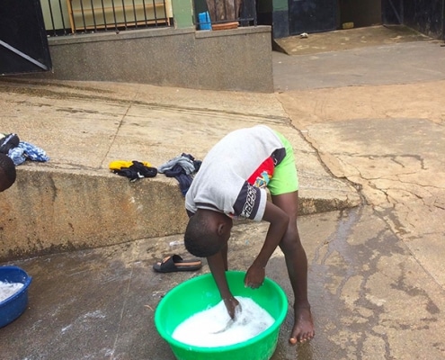 Ugandan street boy washing clothes