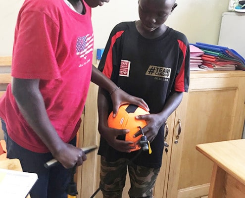 Two street boys inflating a football