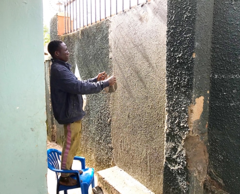 A former street boy now repairing a wall