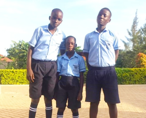 Three former street children in new school uniforms