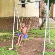 Former street child playing on a swing at Homes of Promise