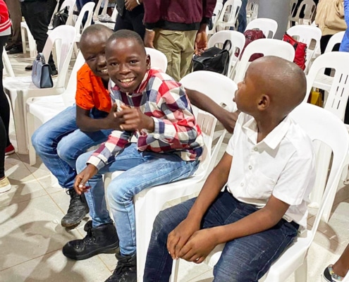 Three former children from the streets of Kampala at church