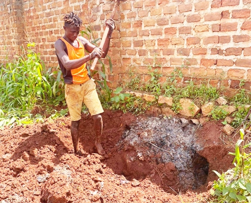 Former street boy cleaning a drainage pipe