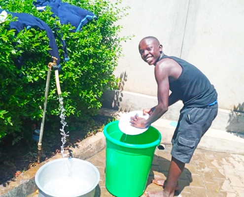Former street boy from Kampala washing plates