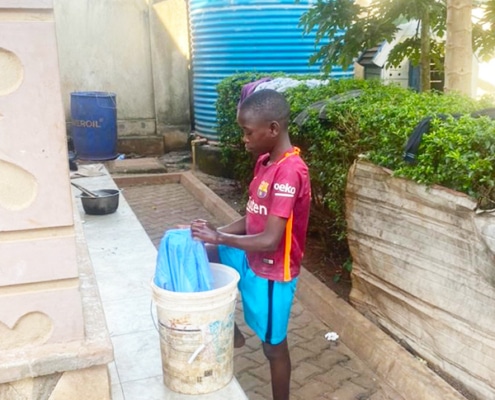 A boy washing his clothes at Homes of Promise