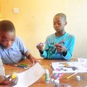 Two former street children from Kampala colouring drawings