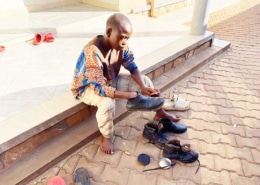 Former street child from Kampala cleaning his shoes