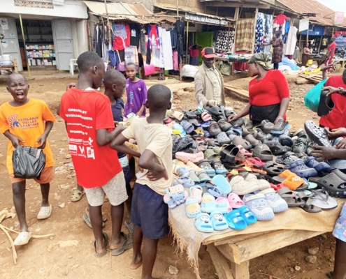 Boys buying sandals at a street market in Uganda