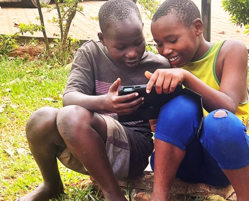 Two former street children playing with Jane's iPad