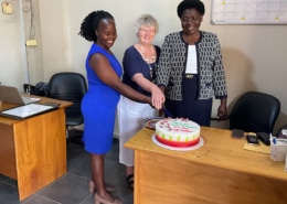 Two of the charity workers cutting a cake with Heather