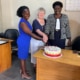Two of the charity workers cutting a cake with Heather